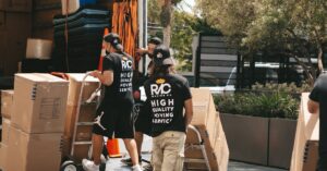 Movers loading boxes into a truck on a sunny day, capturing a busy urban scene.